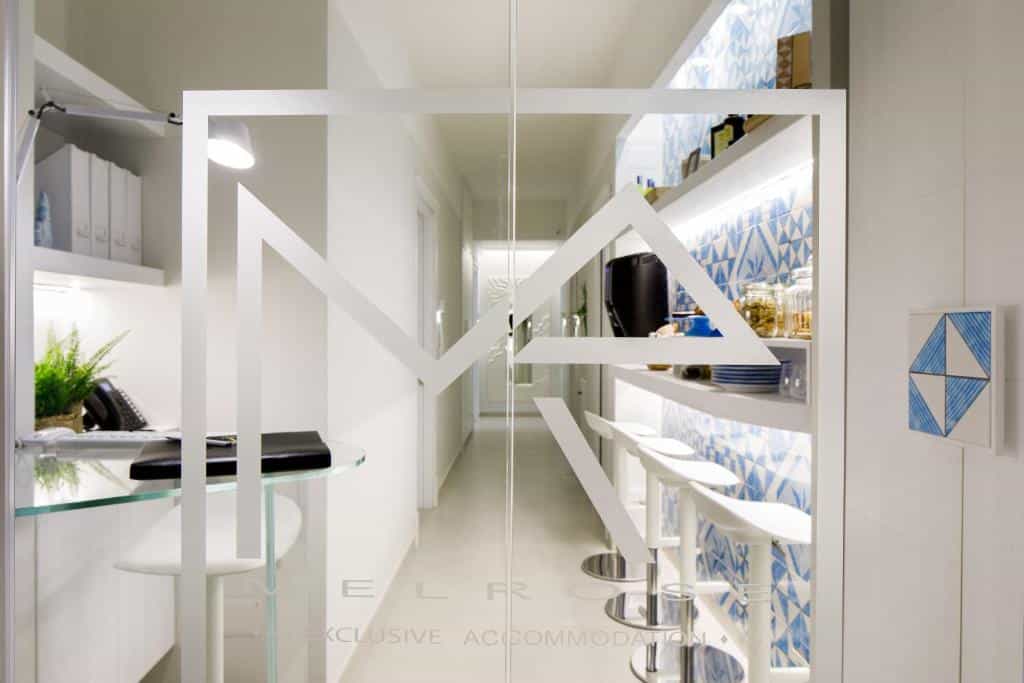 Modern interior with white bar stools, blue patterned tiles, and "MelRose" logo on glass door.