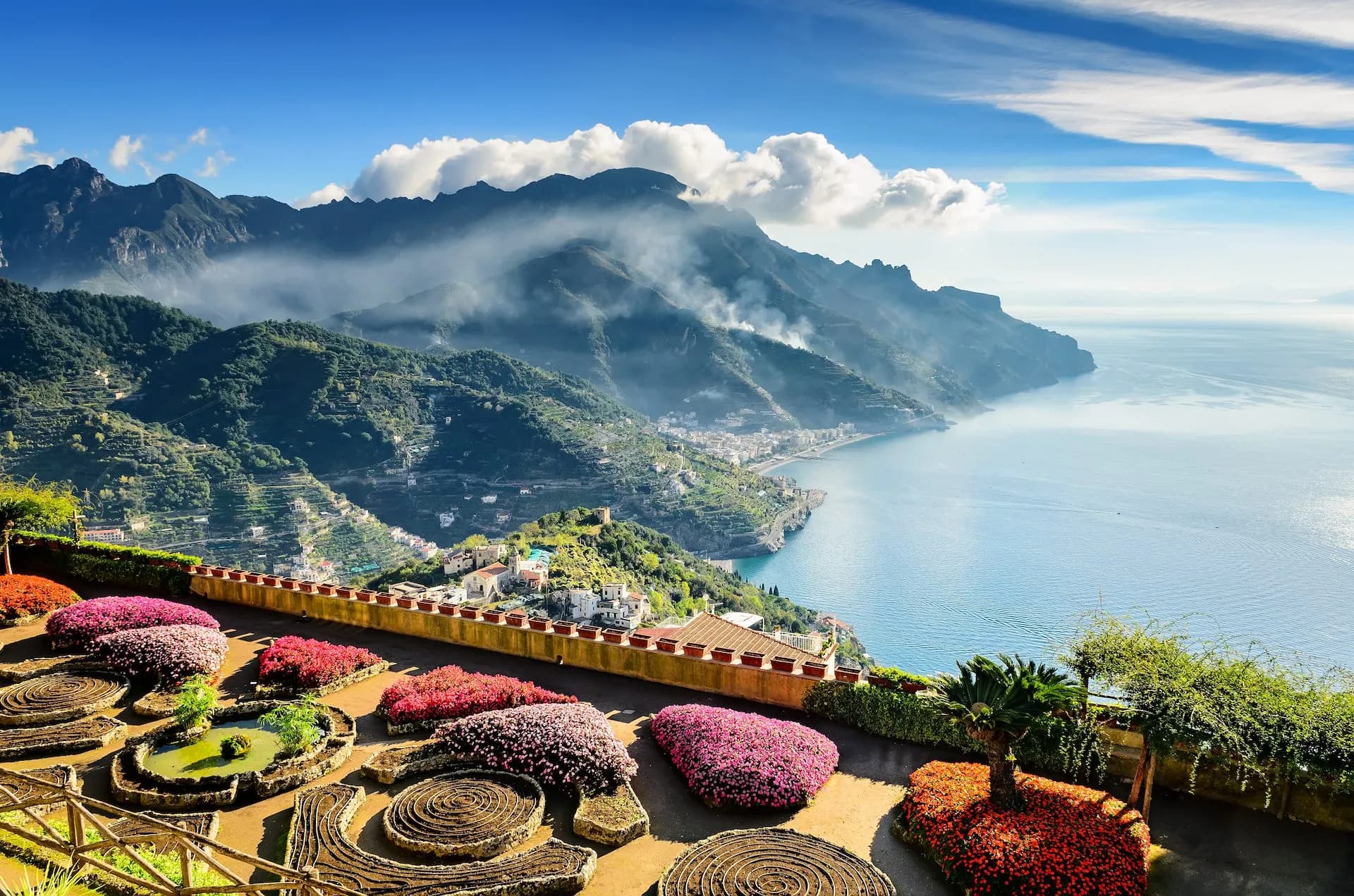 Terraced gardens with colorful flowers overlooking the Amalfi Coast mountains and sea in Ravello.