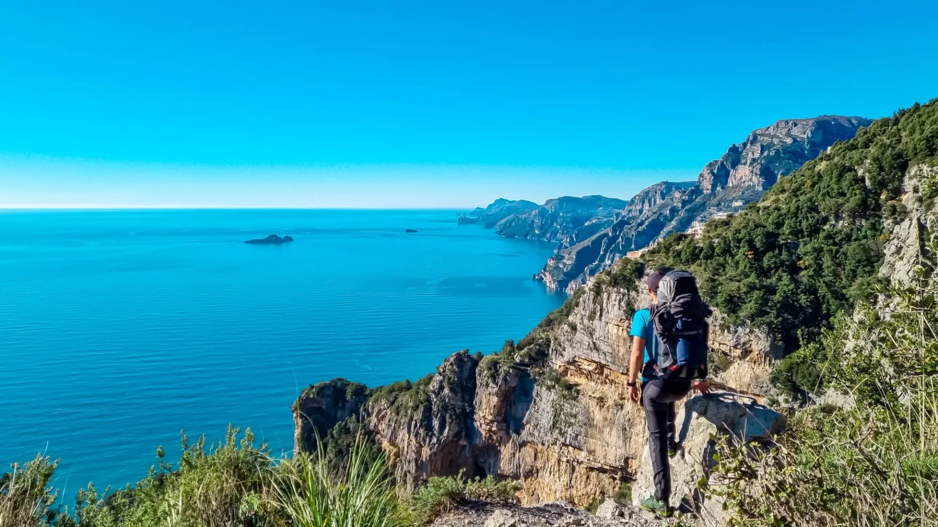 Man with panoramic view from hiking trail Path of Gods between coastal towns Positano and Praiano. Trekking in Lattari Mountains, Apennines, Amalfi Coast, Campania, Italy, Europe. Mediterranean Sea